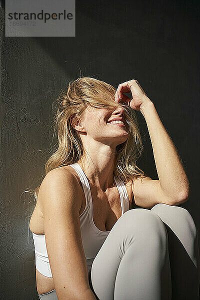Blonde junge Frau lacht im Sonnenlicht