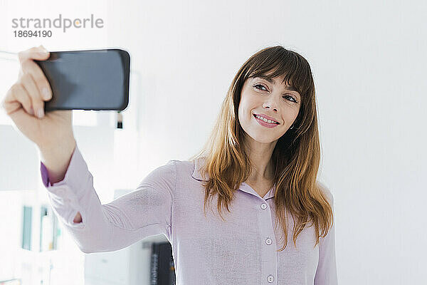 Lächelnde Frau  die ein Selfie mit dem Smartphone macht