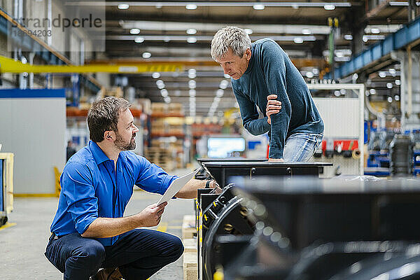 Manager diskutiert mit Manager über Maschinen in der Fabrik