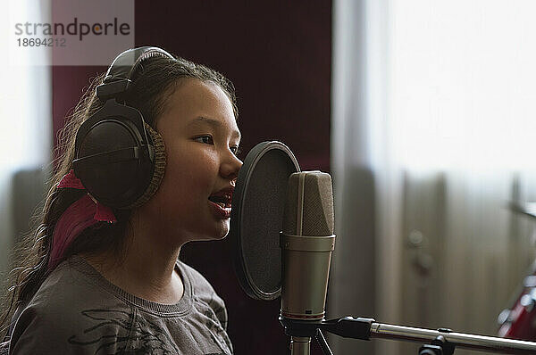 Mädchen nimmt Lied am Mikrofon im Studio auf