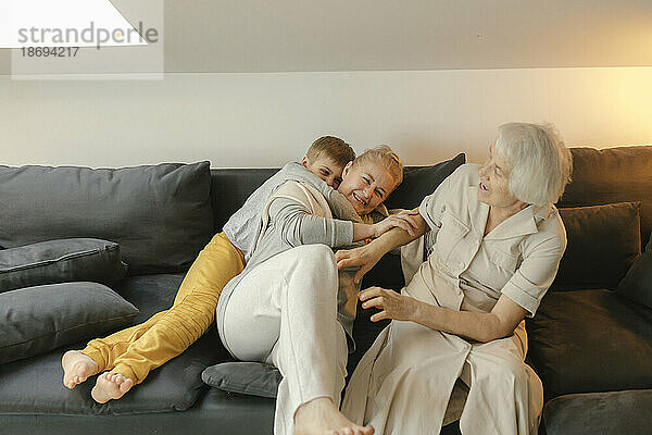 Glückliche Familie genießt es  zu Hause auf dem Sofa zu sitzen