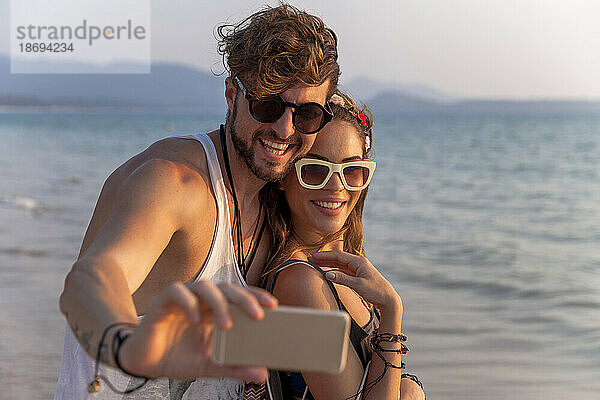 Mann macht Selfie per Handy mit Freundin am Strand