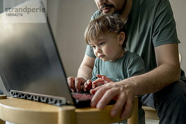 Vater und Sohn benutzen Laptop zu Hause