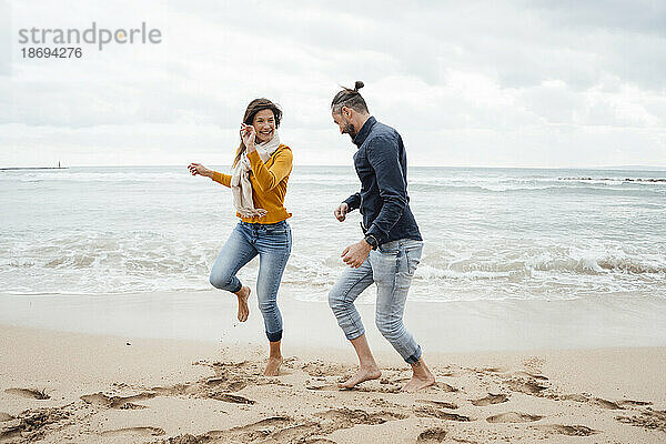 Fröhliches Paar tanzt am Strand vor dem Meer