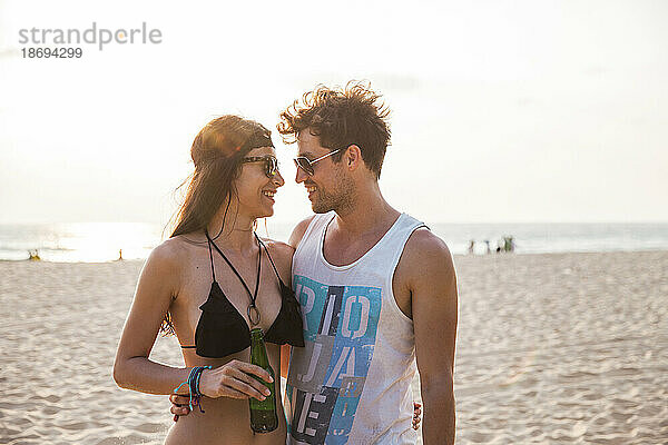 Junges Paar  das sich am Strand umarmt und einander anschaut