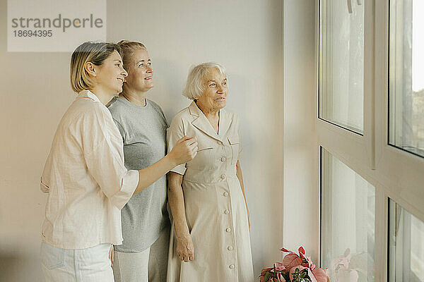 Frauen aus mehreren Generationen schauen zu Hause aus dem Fenster