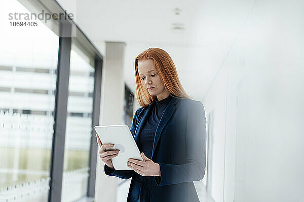 Rothaarige Geschäftsfrau nutzt Tablet-PC im Büro
