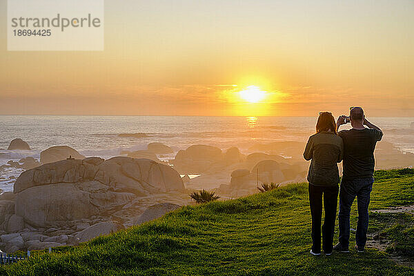 Südafrika  Provinz Westkap  Kapstadt  Touristen fotografieren den Atlantik bei Sonnenuntergang