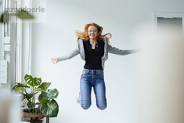 Cheerful woman jumping by plant
