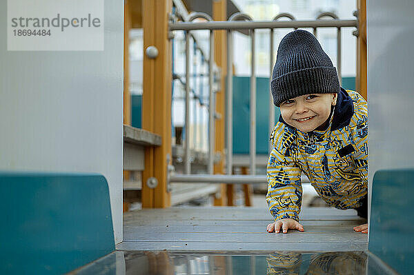 Lächelnder süßer Junge  der auf dem Spielplatz krabbelt