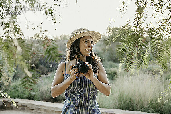 Lächelnde Frau mit Hut und Kamera
