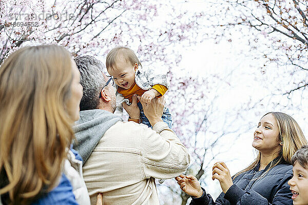 Glücklicher Mann kitzelt Sohn mit Familie im Park