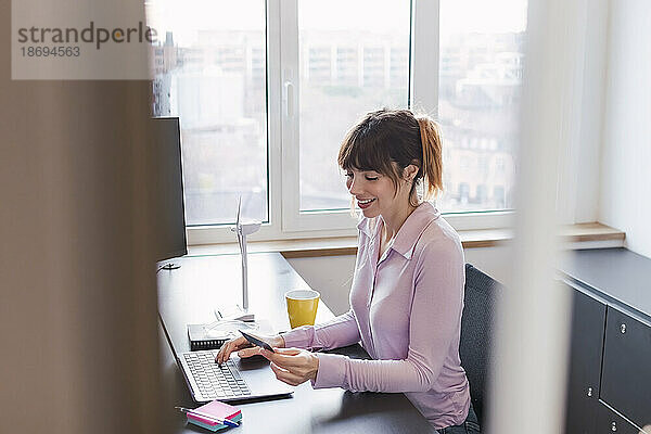 Lächelnde Geschäftsfrau  die im Büro Kreditkarte verwendet