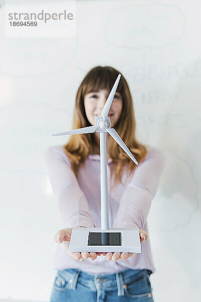 Geschäftsfrau hält Windturbinenmodell vor dem Whiteboard