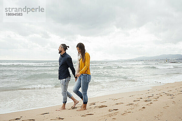 Reifer Mann und Frau gehen gemeinsam an der Küste am Strand spazieren