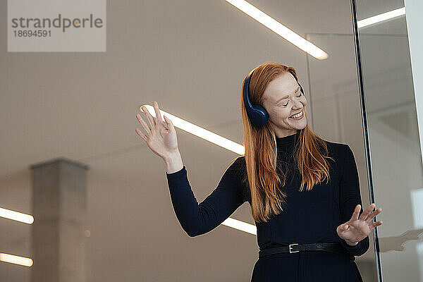 Glückliche Geschäftsfrau  die im Büro gerne Musik hört