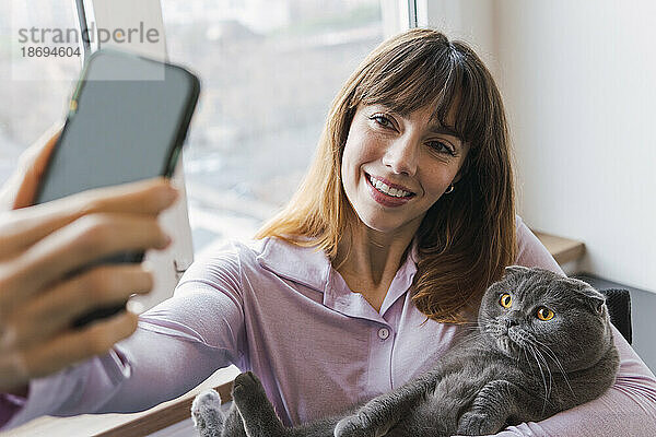Glückliche Frau macht Selfie mit Katze per Smartphone