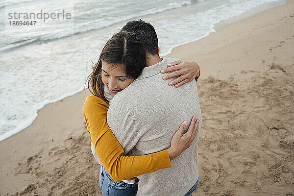 Smiling woman hugging man at beach