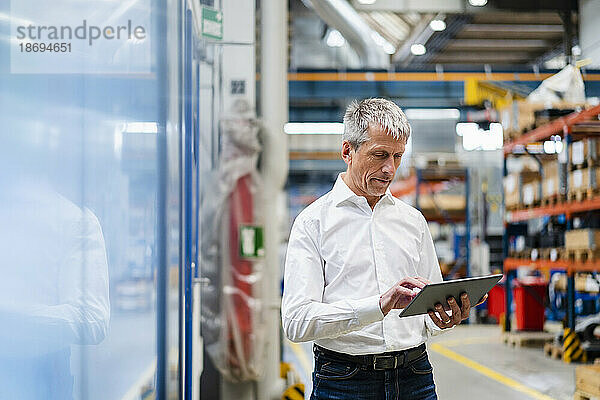 Reifer Geschäftsmann nutzt Tablet-PC in der Fabrik