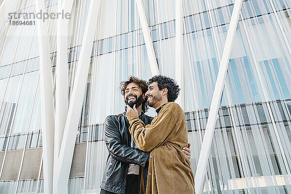 Glückliches  liebevolles schwules Paar  das vor dem Gebäude steht