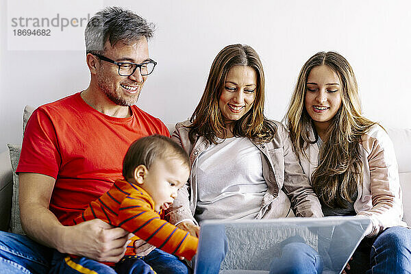 Lächelnde Familie schaut zu Hause gemeinsam auf den Laptop