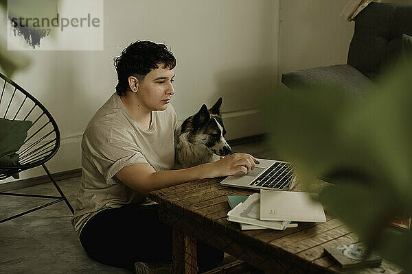 Freiberufler nutzt Laptop und sitzt mit Hund zu Hause