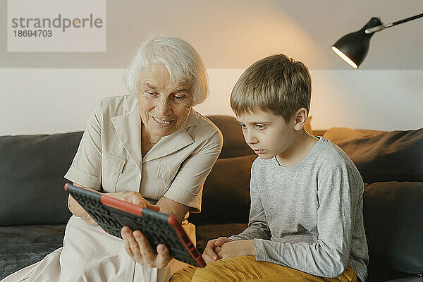 Großmutter und Enkel schauen sich zu Hause Videos auf einem Tablet-PC an