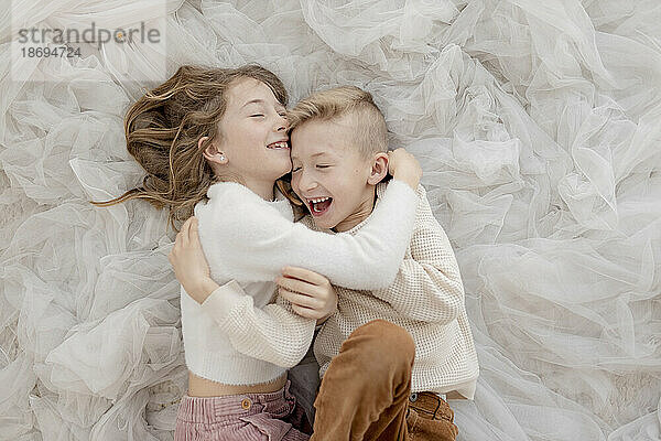 Brother and sister lying on tulle net