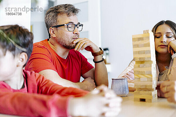 Nachdenklicher Vater spielt zu Hause mit der Familie ein Blockentfernungsspiel