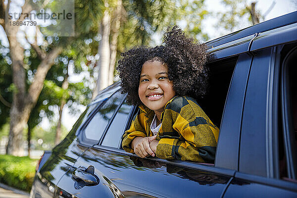 Smiling girl leaning outside car window