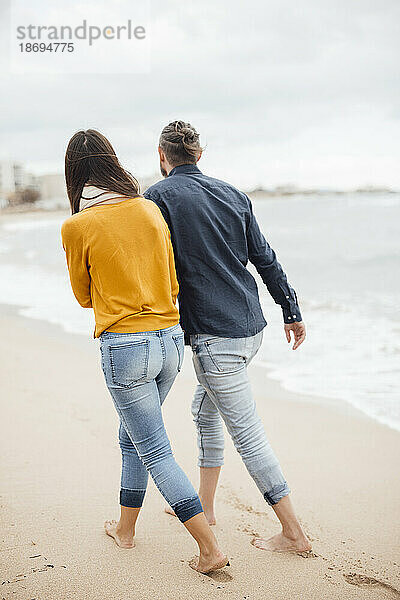 Mann und Frau gehen gemeinsam am Strand spazieren