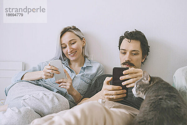 Happy couple using smart phone at home