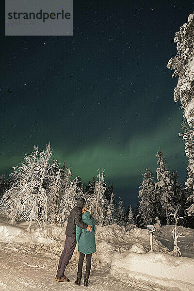Couple looking at Aurora Borealis on sky at night