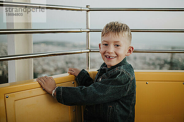 Lächelnder Junge sitzt im Riesenrad im Vergnügungspark