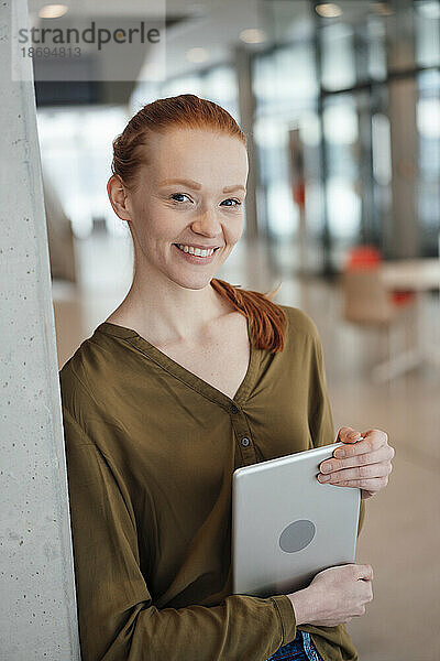 Lächelnde Geschäftsfrau hält Tablet-PC im Büro