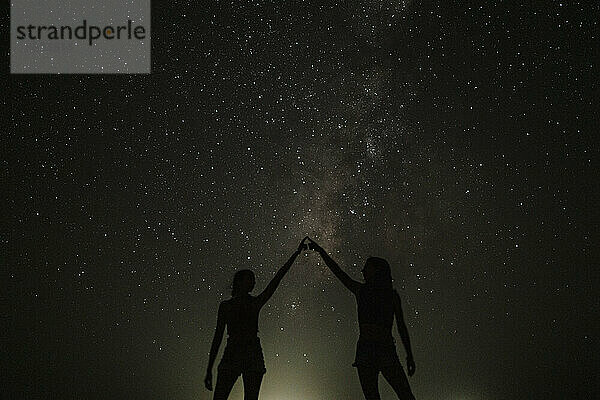Zwei Frauen berühren Finger und stehen vor Sternen