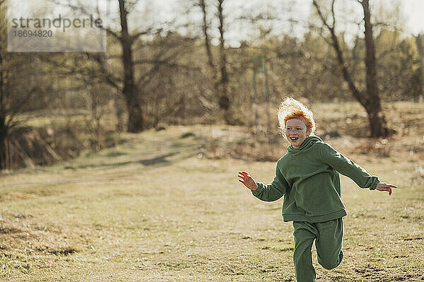 Unbekümmertes Mädchen läuft an sonnigem Tag im Wald