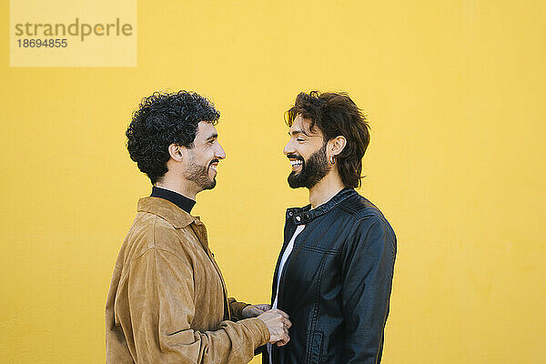 Happy gay men with face to face against yellow background