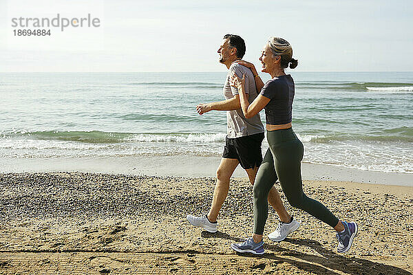 Glückliches Paar läuft und hat Spaß am Strand