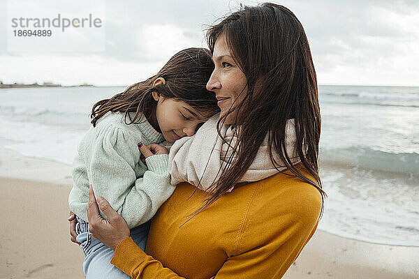 Lächelnde Frau mit Tochter am Strand