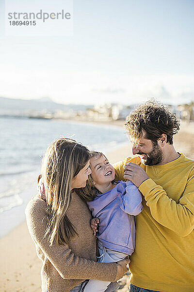 Vater und Mutter spielen mit Tochter am Strand