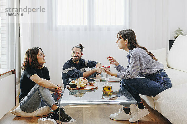 Lächelnde Kunden diskutieren mit einem Ernährungsberater  der zu Hause auf dem Sofa sitzt