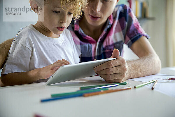 Vater und Sohn nutzen Tablet-PC am Schreibtisch