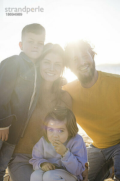 Lächelnde Eltern mit Sohn und Tochter am Strand an einem sonnigen Tag