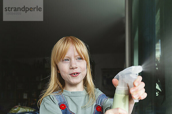 Redhead girl spraying chemical from spray bottle