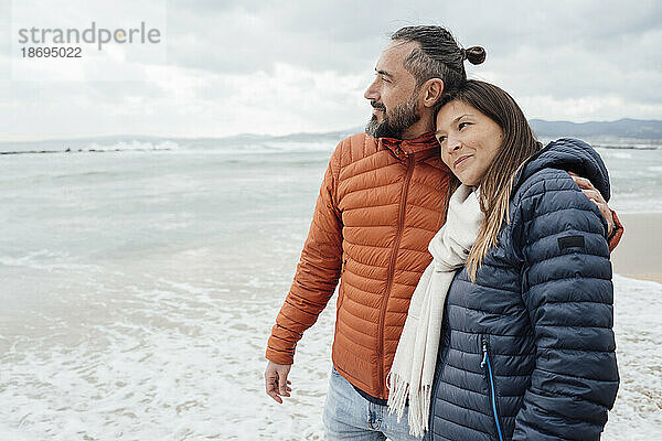 Lächelnder Mann und Frau stehen an der Küste am Strand