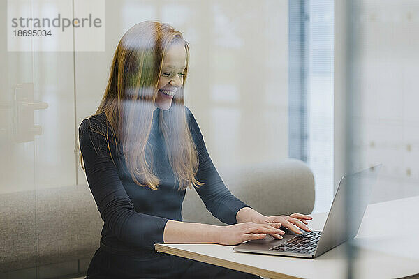 Lächelnde Geschäftsfrau  die in einer Bürokabine arbeitet