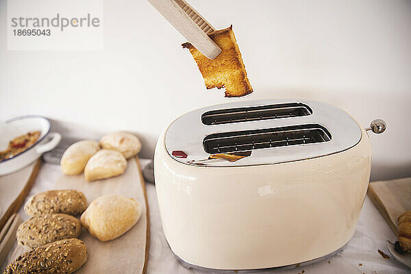 Cooking tongs removing bread toast from toaster