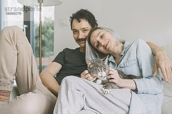 Happy man and woman with cat sitting at home