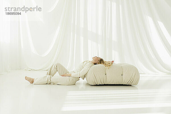 Woman relaxing on cushion by translucent couch